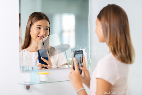 Image of teenage girl looking in mirror and taking selfie