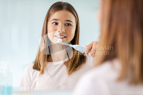 Image of teen girl with electric toothbrush brushing teeth