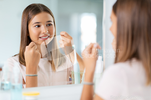 Image of teenage girl with floss cleaning teeth at bathroom