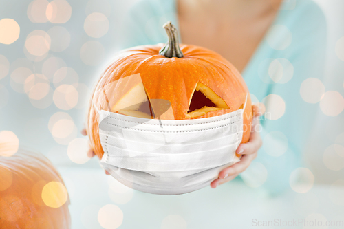 Image of close up of woman holding pumpkin in mask