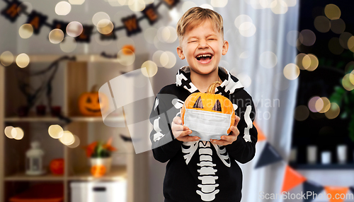 Image of happy boy with pumpkin in mask on halloween