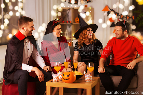 Image of happy friends in halloween costumes at home party