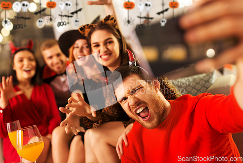 Image of happy friends in halloween costumes taking selfie