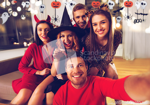 Image of happy friends in halloween costumes taking selfie