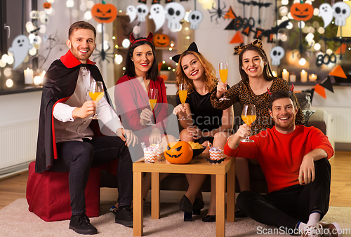 Image of happy friends in halloween costumes at home party