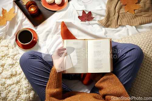 Image of young woman reading book at home in autumn