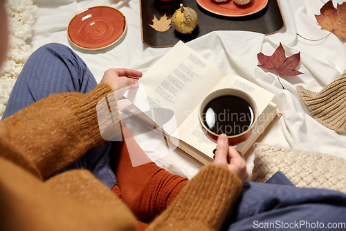 Image of woman drinking coffee and reading book in autumn