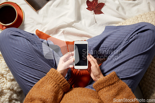 Image of woman with smartphone at home in autumn