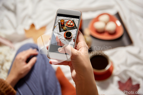 Image of woman with smartphone taking picture of autumn set