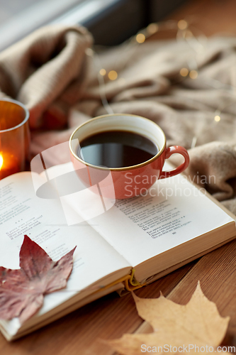 Image of cup of coffee, book on window sill in autumn