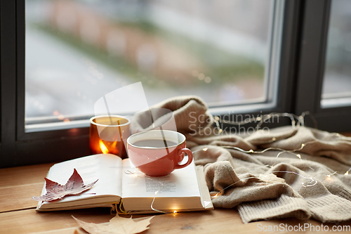 Image of cup of coffee, book on window sill in autumn