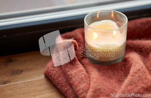 Image of woolen sweater and candle burning on window sill