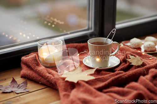 Image of cup of tea and candle on window sill in autumn