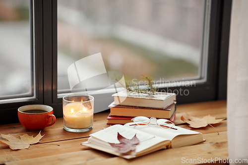 Image of book, coffee and candle on window sill in autumn