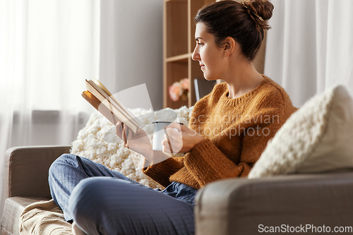 Image of woman drinking coffee and reading book at home