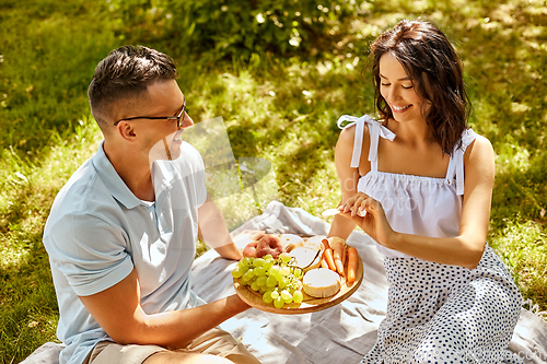 Image of happy couple having picnic at summer park