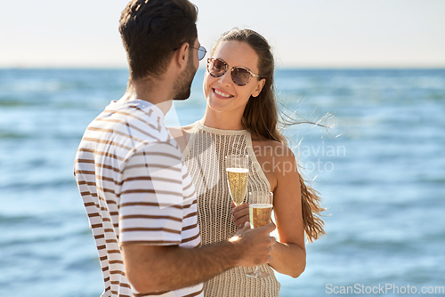 Image of happy couple drinking champagne on summer beach