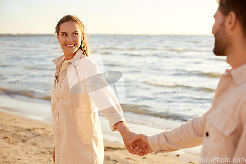 Image of happy couple holding hands on summer beach