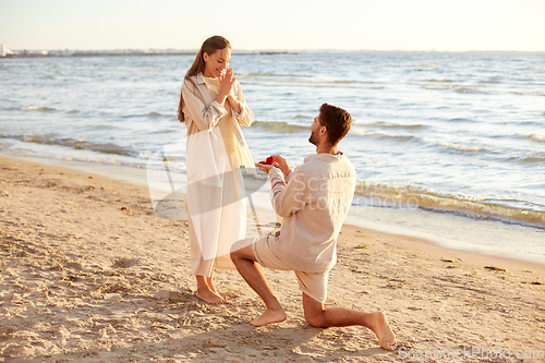 Image of man with ring making proposal to woman on beach