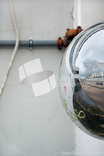 Image of cityscape reflected on convex parking mirror