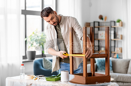 Image of man with ruler measuring table for renovation