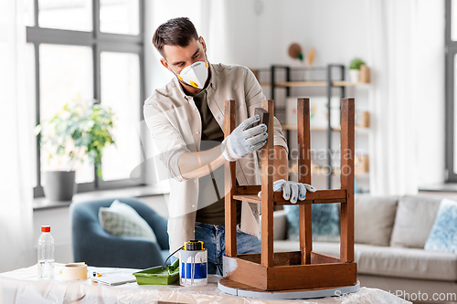 Image of man in respirator sanding old table with sponge