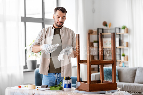 Image of man applying solvent to rag for cleaning old table