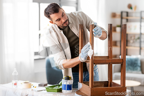 Image of man cleaning old table surface with tissue