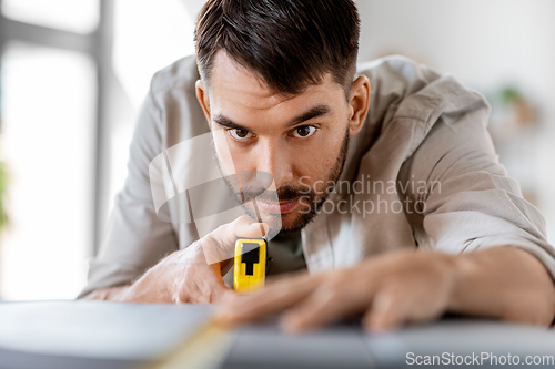 Image of man with ruler measuring table for renovation