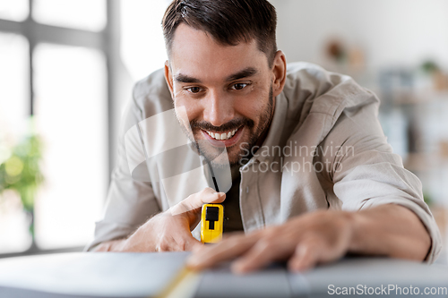 Image of man with ruler measuring table for renovation