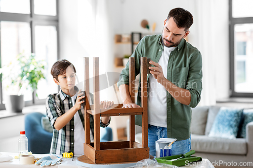 Image of father and son sanding old table with sponge