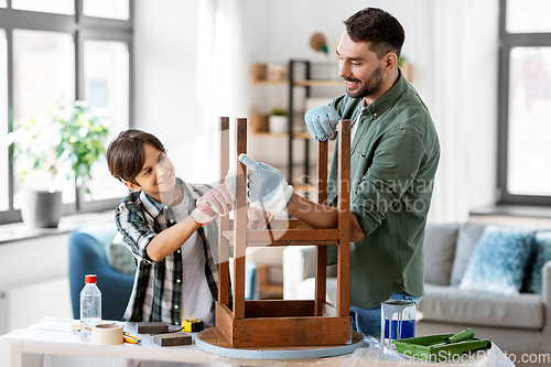 Image of father and son cleaning old table with tissue