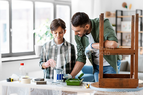 Image of father and son stirring grey color paint at home