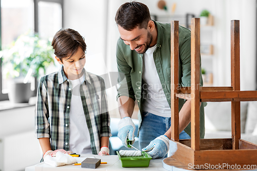 Image of father and son painting old table at home