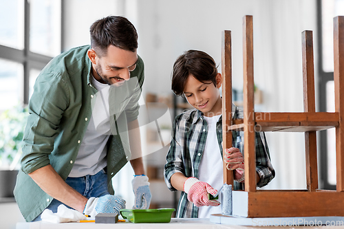 Image of father and son painting old table in grey color