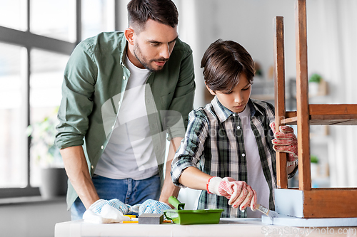 Image of father and son painting old table in grey color