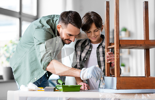 Image of father and son painting old table in grey color