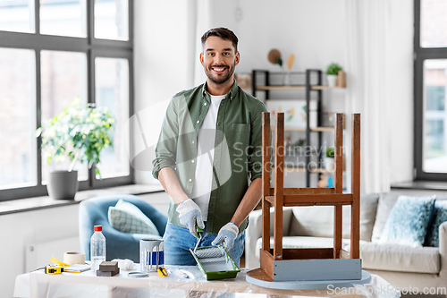 Image of man painting old table in grey color at home