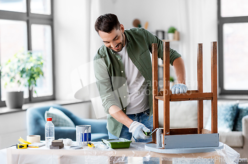 Image of man painting old table in grey color at home