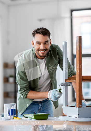 Image of man painting old table in grey color at home