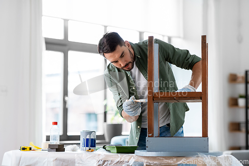 Image of man painting old wooden table in grey color