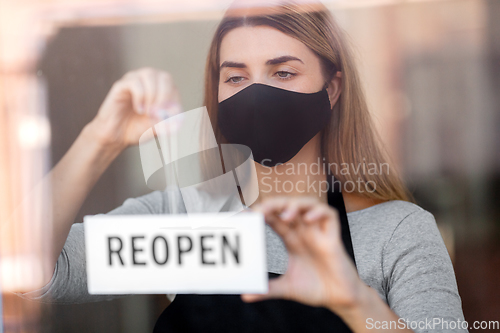 Image of woman in mask with reopen banner on door glass