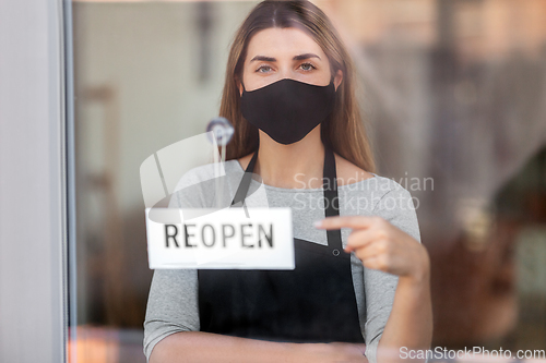 Image of woman in mask with reopen banner on door glass