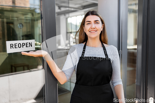 Image of happy woman showing reopen banner on door glass