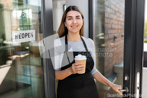 Image of happy woman with coffee and reopen banner on door