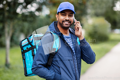 Image of indian delivery man with bag calling on smartphone