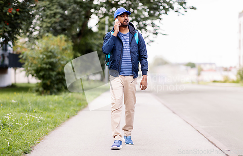 Image of indian delivery man with bag calling on smartphone