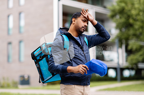 Image of tired indian delivery man with bag in city