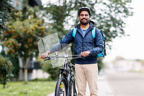 Image of indian delivery man with bag and bicycle in city