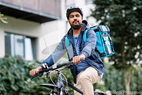 Image of indian delivery man with bag riding bicycle